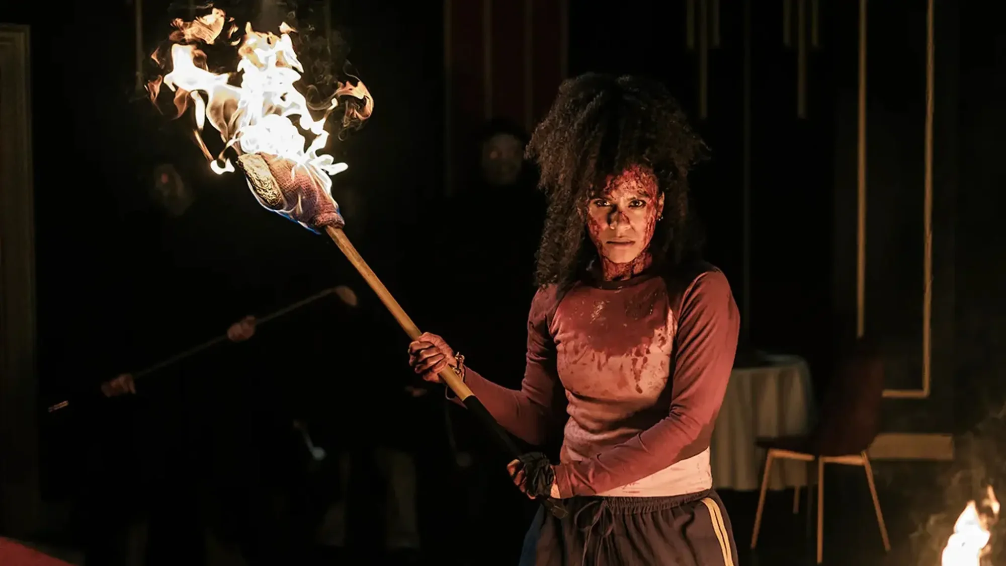 Bloodied Zazie Beetz holding a fiery axe in They Will Kill You