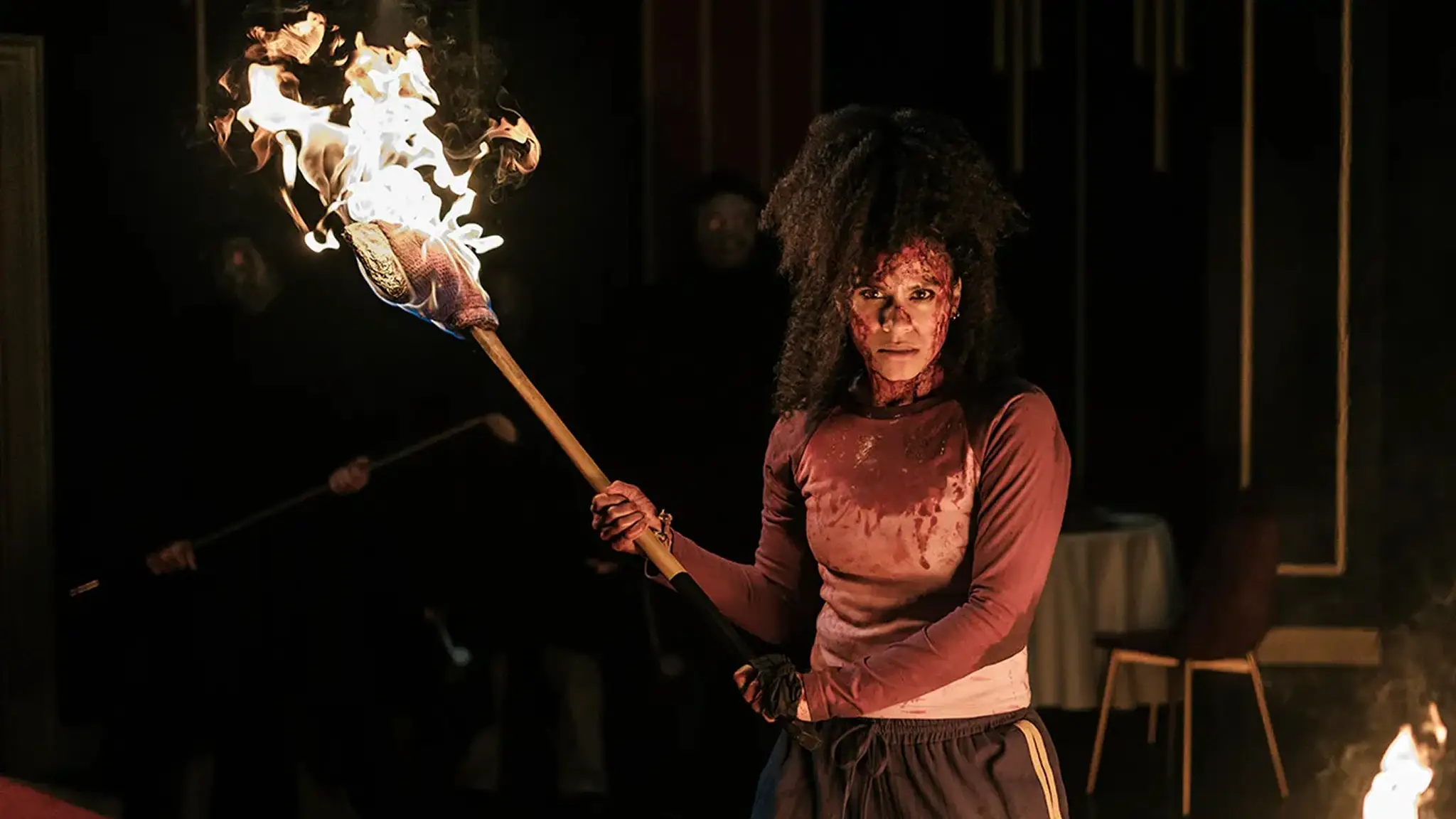 Bloodied Zazie Beetz holding a fiery axe in They Will Kill You
